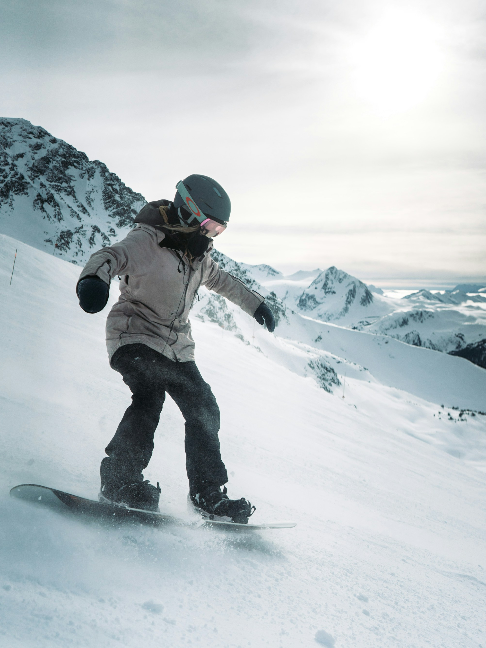 Snow goggles and ski board displayed against a snowy mountain backdrop with clear blue skies, emphasizing premium quality and dynamic performance.